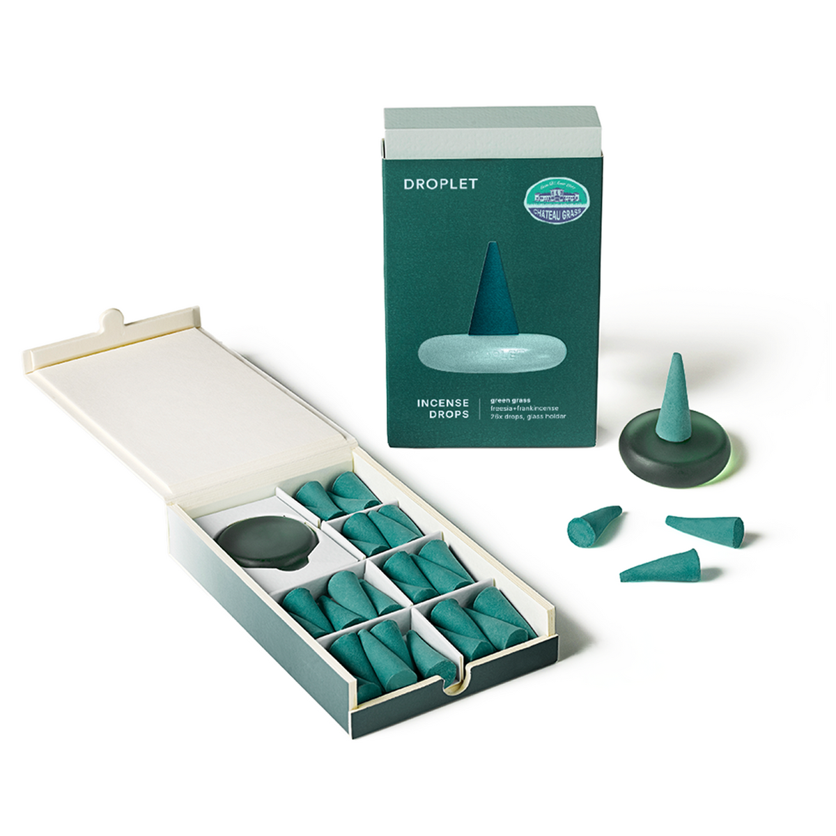 An open box of green tea incense drops with a matching product box standing behind it, plus a few loose incense pieces on a clean white background.