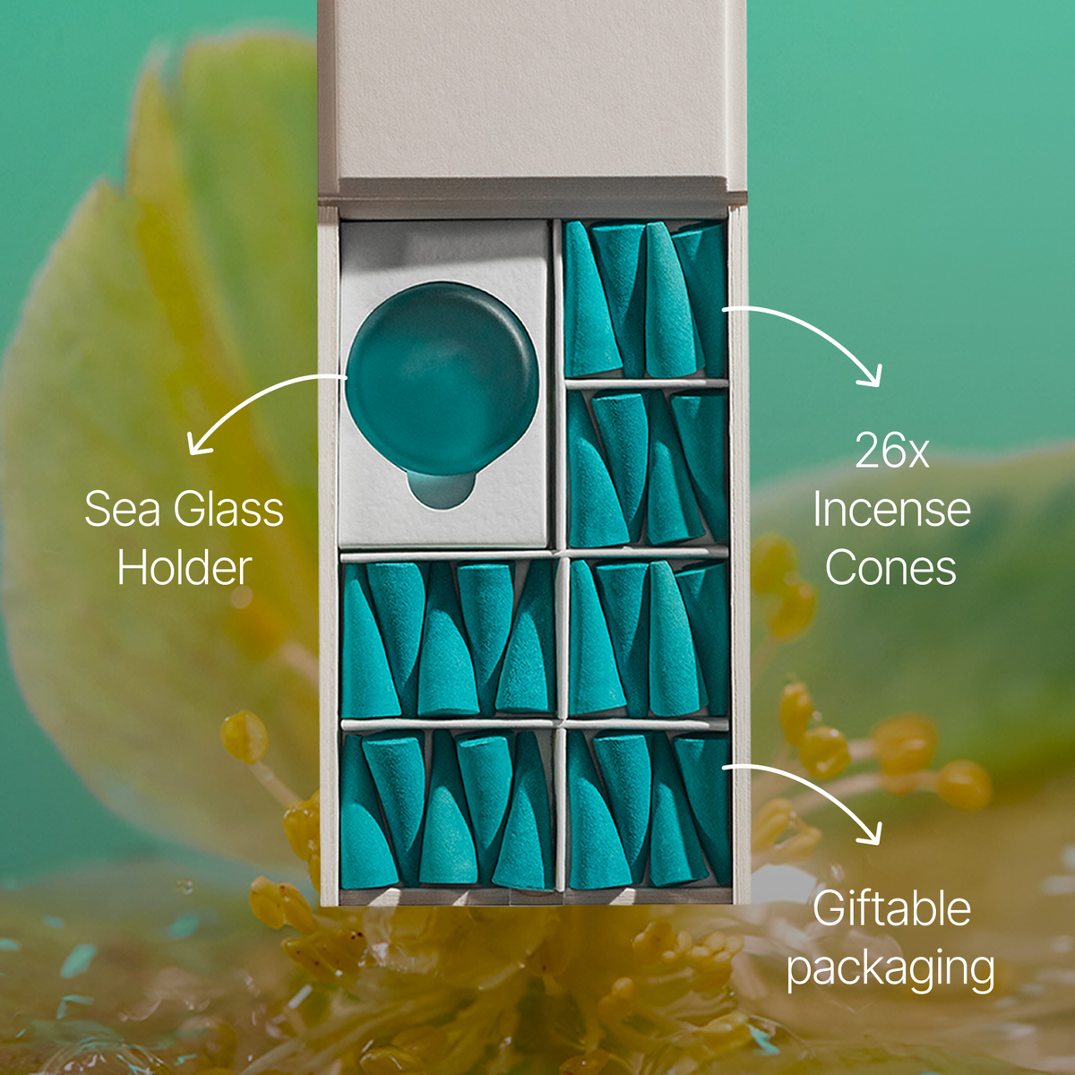 An open white box containing a teal sea glass holder and 26 teal incense cones, with callout labels reading 'Sea Glass Holder,' '26x Incense Cones,' and 'Giftable packaging' over a soft green background with blurred botanical elements.