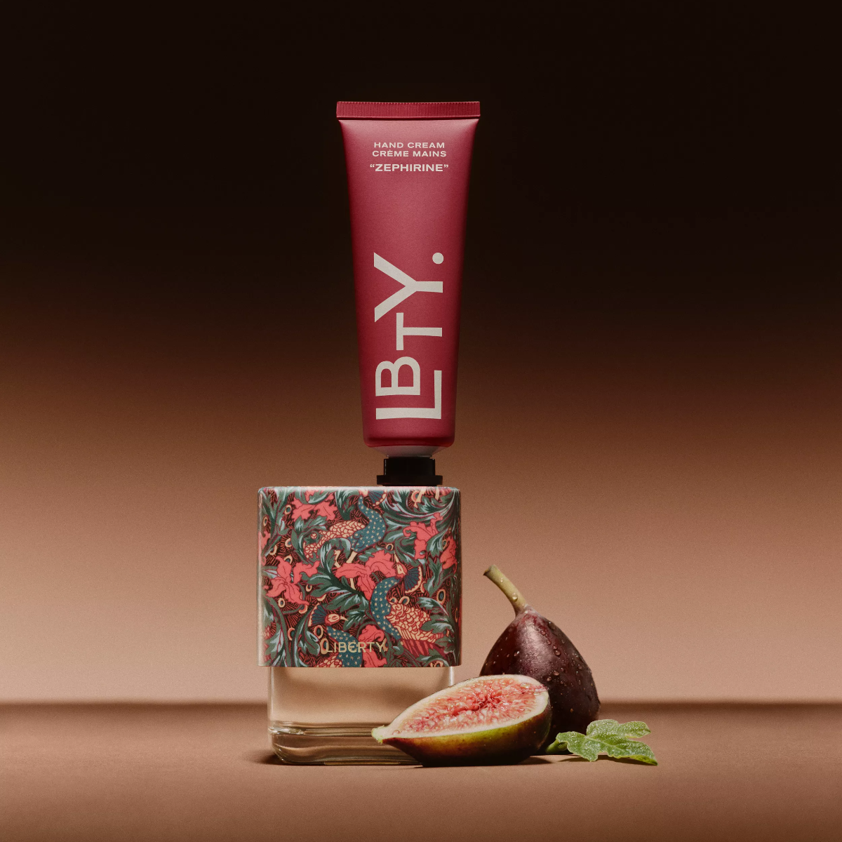Perfume bottle with floral design, red tube, and fig fruit on a brown background