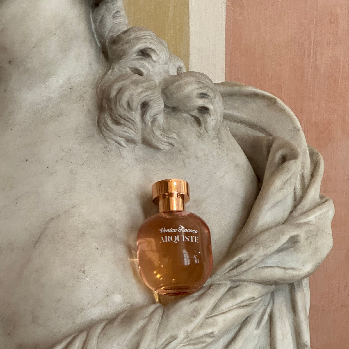 A bottle of Arquiste Venice Rococo perfume on a part of a statue