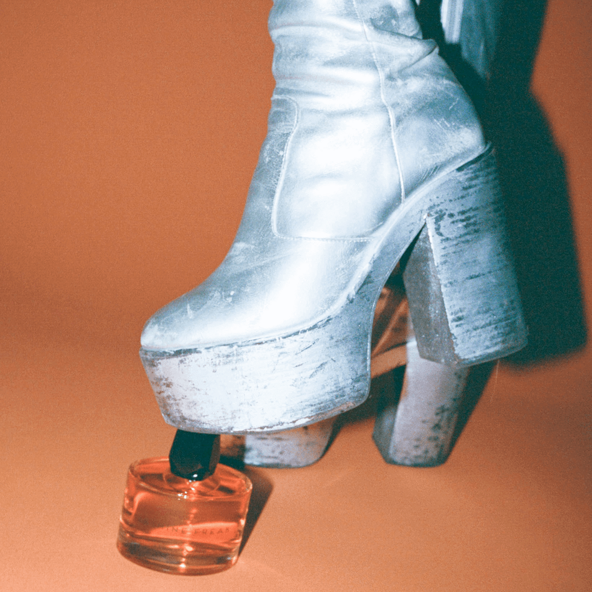 Room 1015 Jasmine Freak - Eau de Parfum bottle under a foot in a silver, chunky heel on a tan background
