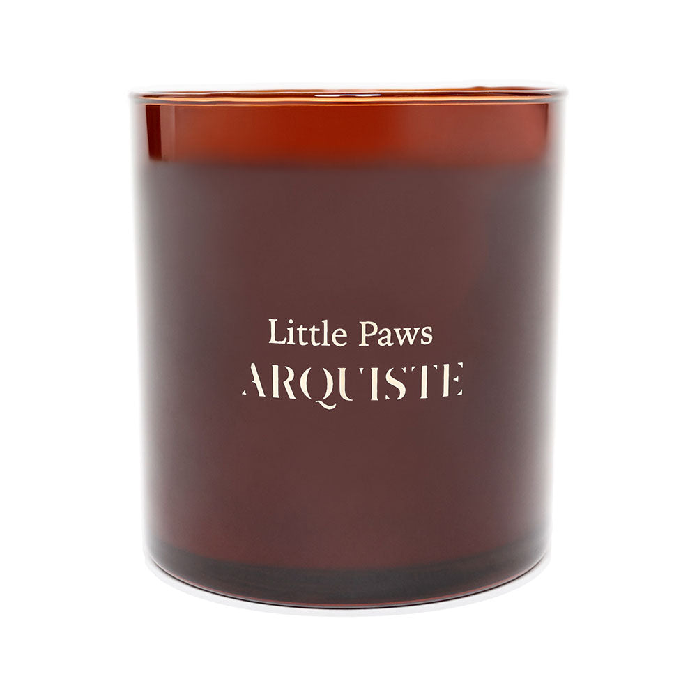A brown glass jar candle with white label reading 'Little Paws ARQUISTE'.