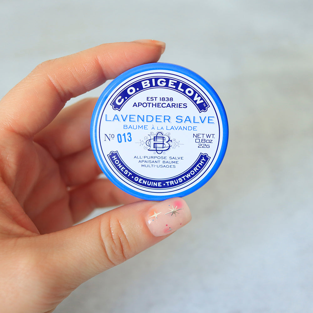 C. O. Bigelow Lavender Salve container held by a hand against a light background