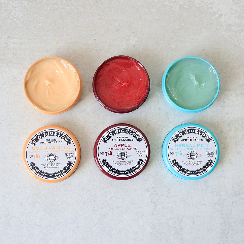 Collection of Bigelow Apothecary containers with different colored lids on a light background