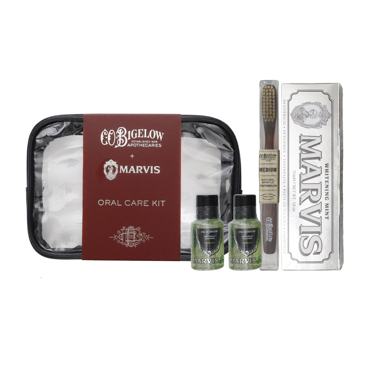 A Bigelow Apothecaries and Marvis oral care kit arranged on a white background, including a black travel case, two small green bottles, a toothbrush, and a silver Marvis toothpaste box.
