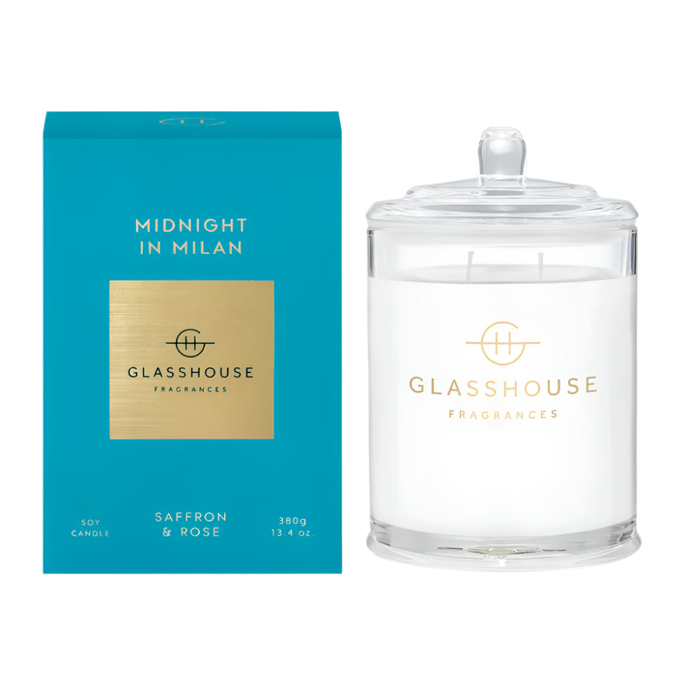Glasshouse Fragrances Midnight in Milan Candle is shown with its lid on next to the light blue box it comes in.  It is a clear glass vessel with a lid and Glasshouse Fragrances Logo on the vessel. 