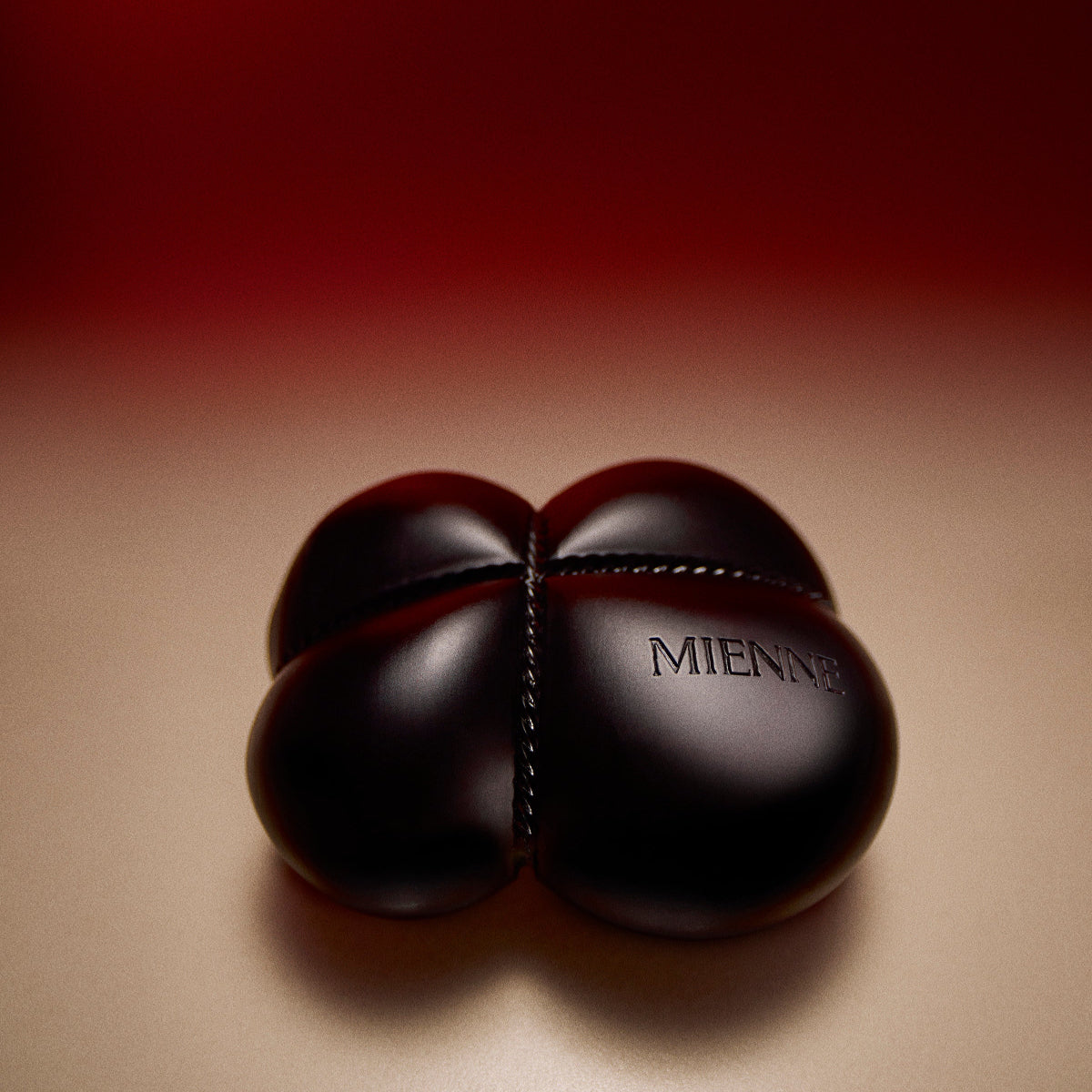 Mienne Bar Soap on a tan surface that fades into red. 