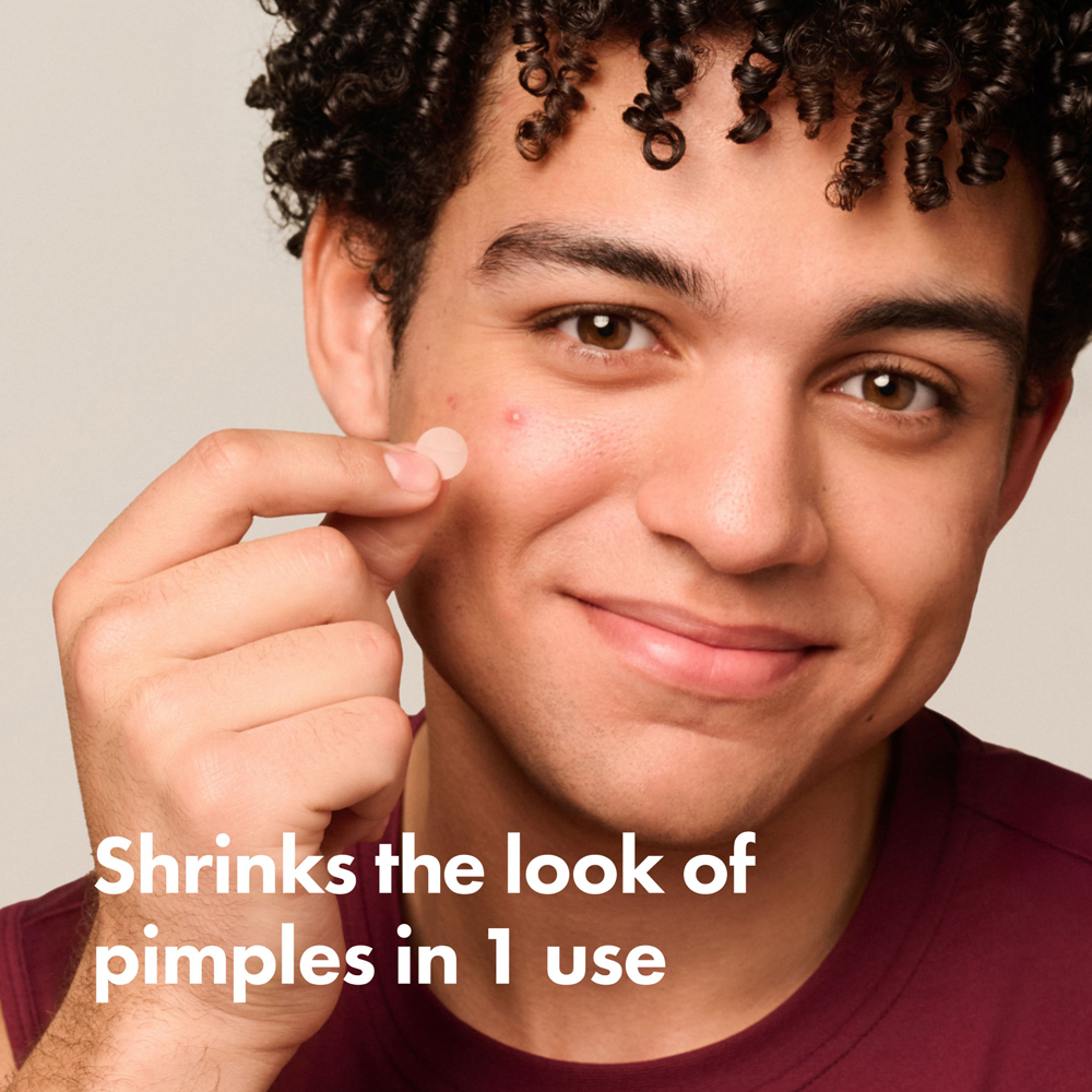 Person pointing to a pimple with text 'Shrinks the look of pimples in 1 use' on a plain background