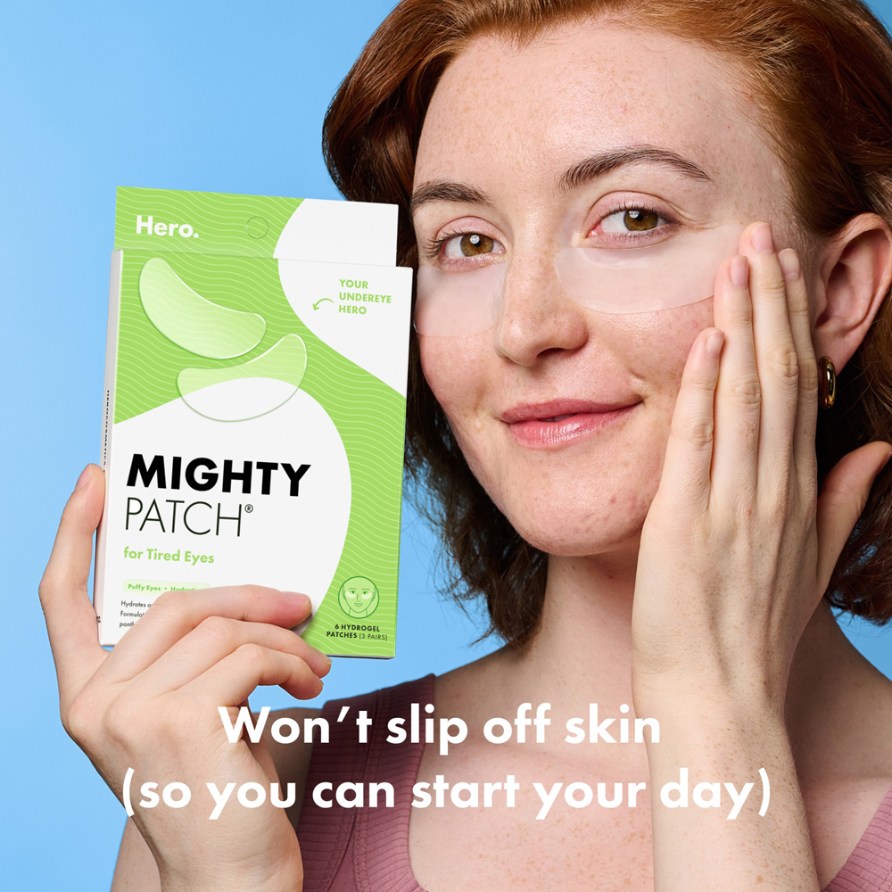 Woman holding a box of Mighty Patch eye patches with a blue background