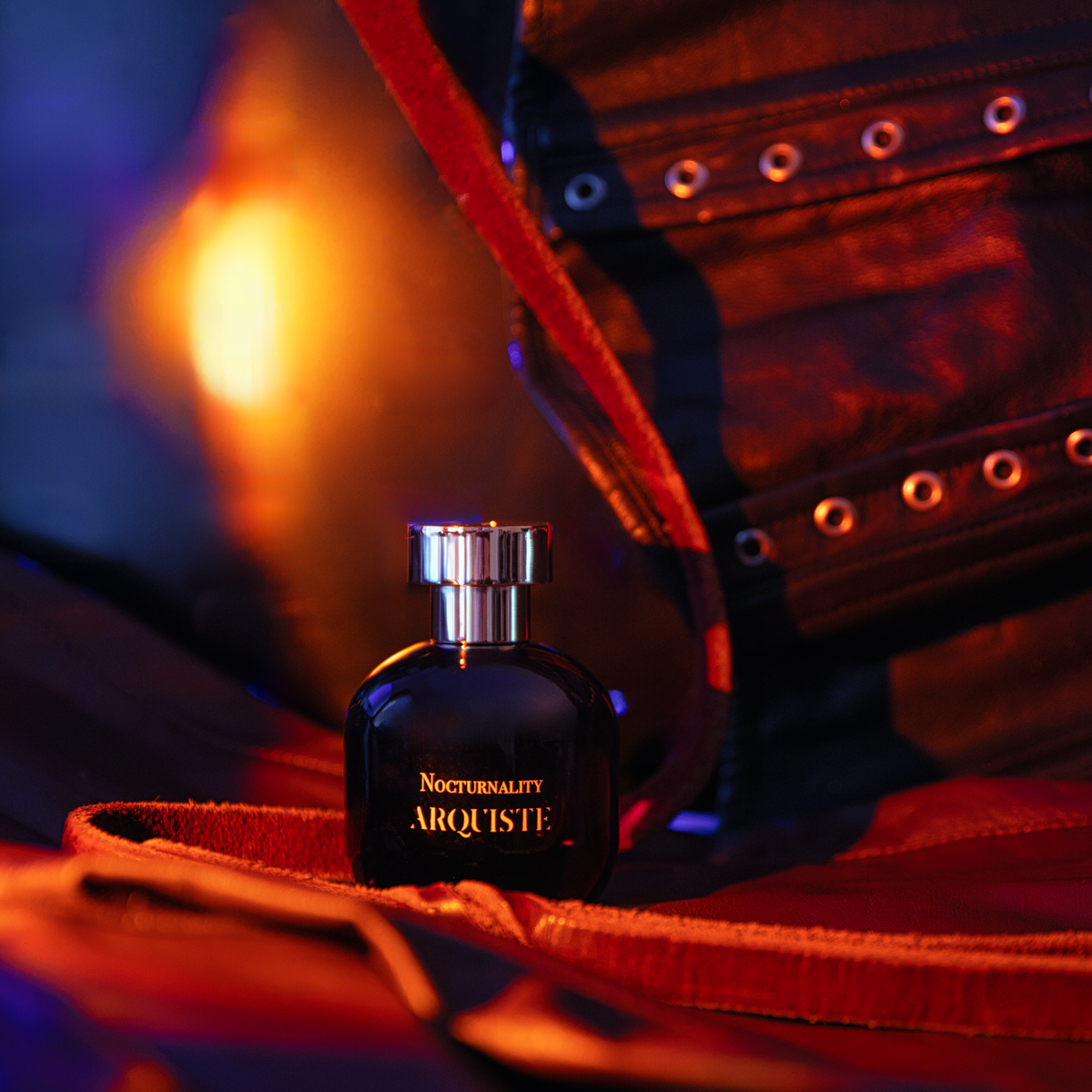 Arquiste Perfume bottle on a red leather surface with a blurred background