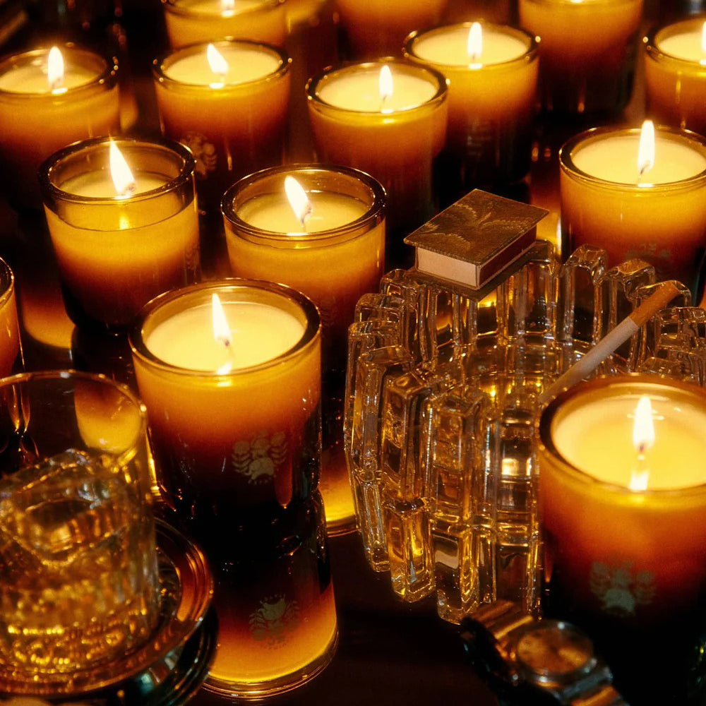 Candlelit scene with lit candles and a crystal holder on a reflective surface.