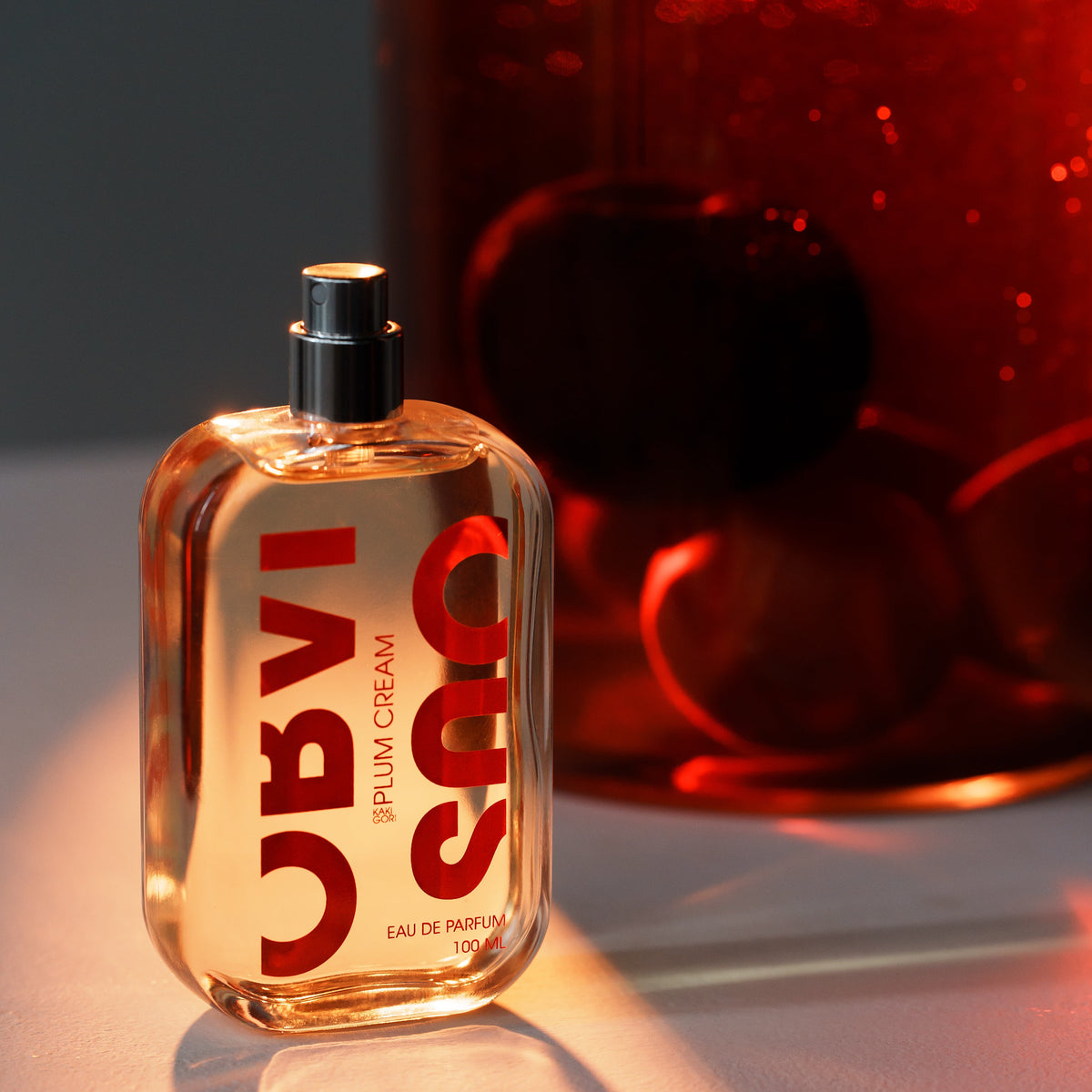 Perfume bottle on a reflective surface with a blurred red background