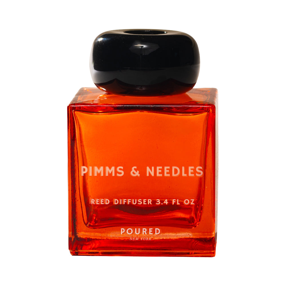 Red reed diffuser bottle with black cap on a white background