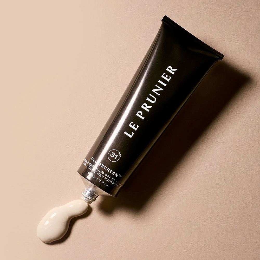Le Prunier Plumscreen SPF 31 Tube flat on a tan background with a dollop of product squeezed out.