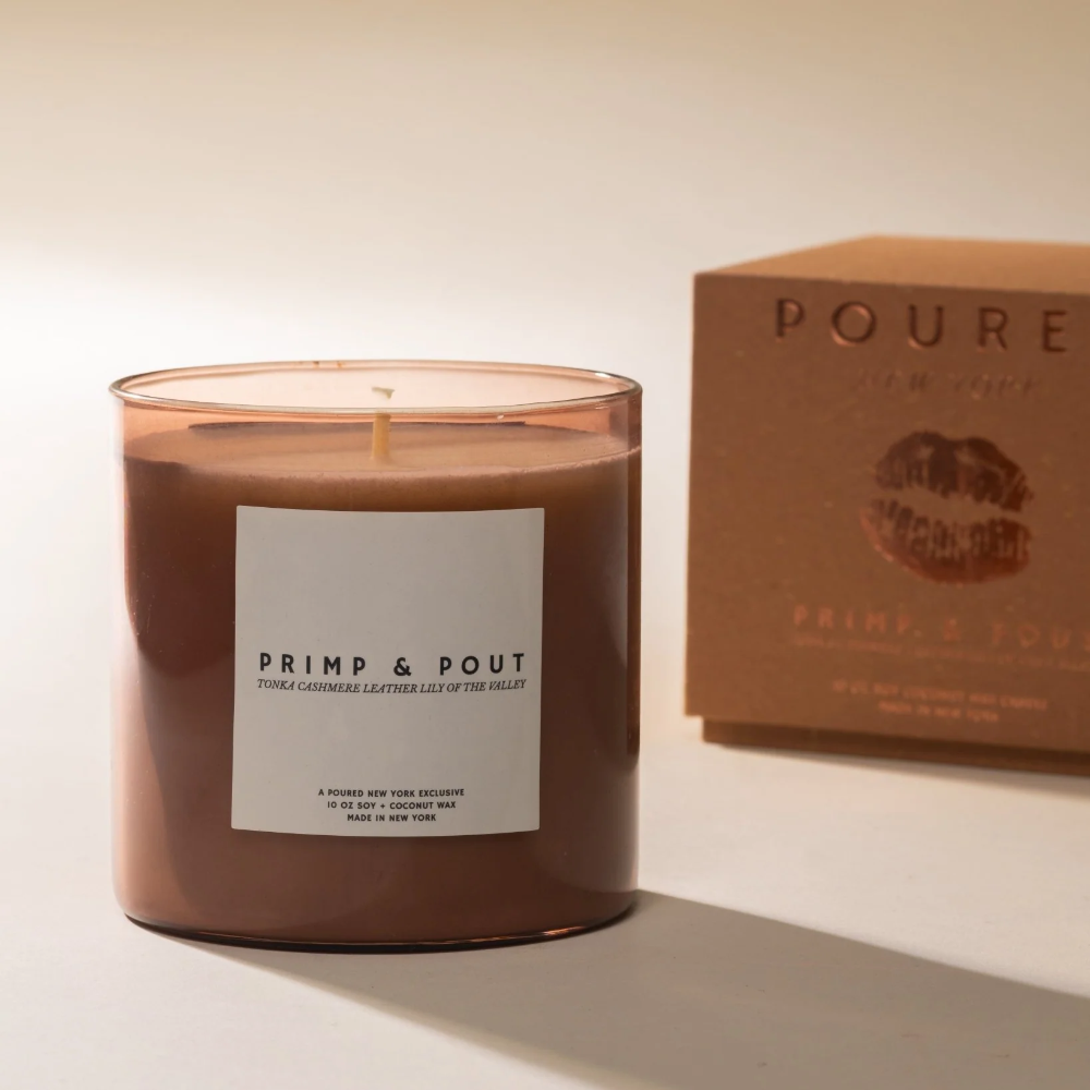 Candle labeled 'Primp & Pout' with a matching box on a neutral background