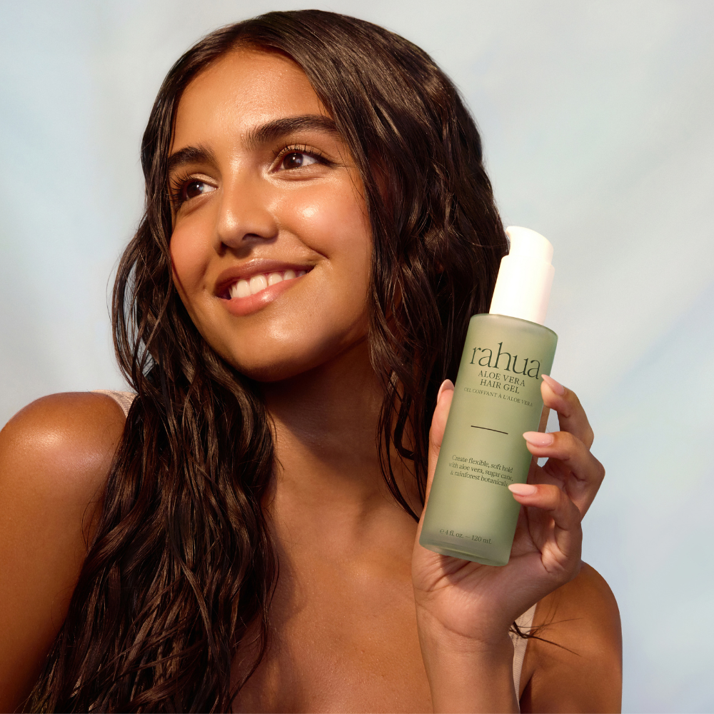 Woman holding a bottle of 'rahu' hair gel with a blurred background