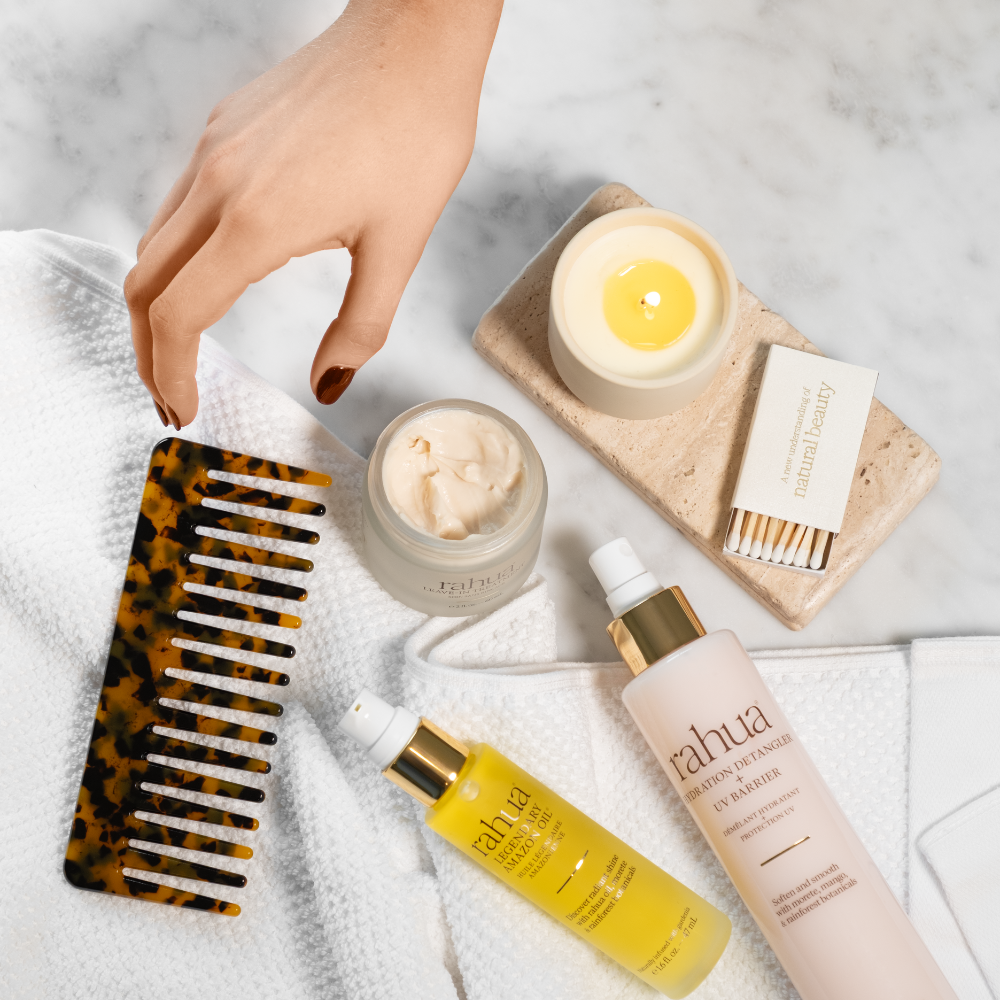 Skincare products and a comb on a textured surface with a candle in the background