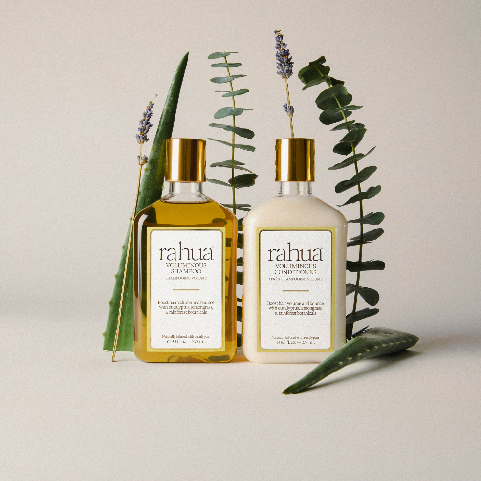 Rahua shampoo and conditioner bottles with plants on a neutral background