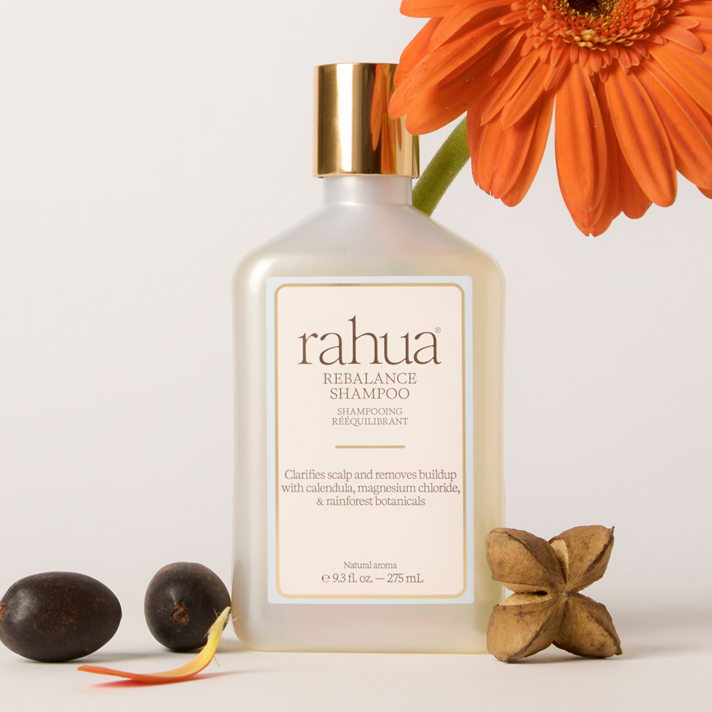 Rebalance Shampoo bottle with natural and floral items around it on a white background