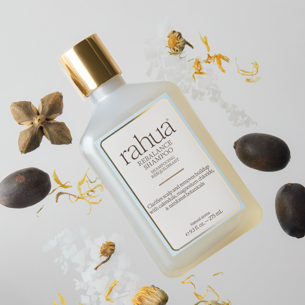 Rebalance Shampoo bottle with natural and floral items around it floating in a white space
