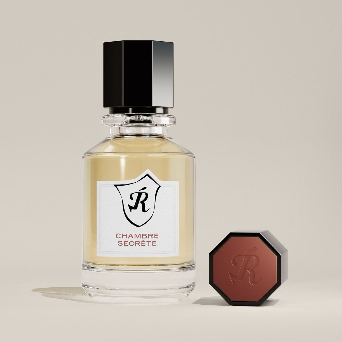 Perfume bottle labeled 'Chambre Secrète' with a hexagonal black cap on a beige background