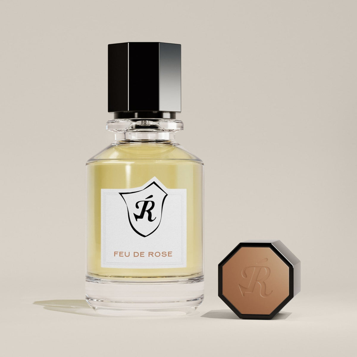 Perfume bottle labeled 'Feu de Rose' with a matching hexagonal compact on a beige background