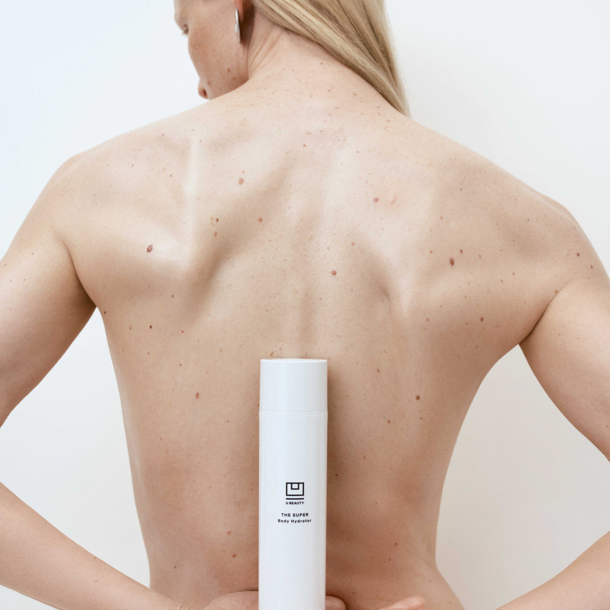 Person holding a white cylindrical product against a plain background