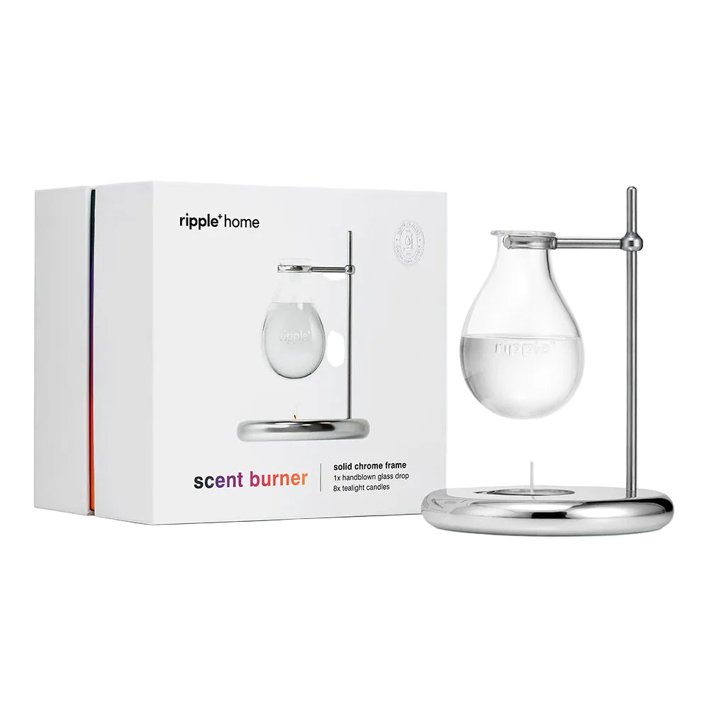 Scent burner with chrome frame and glass container next to its packaging box on a white background