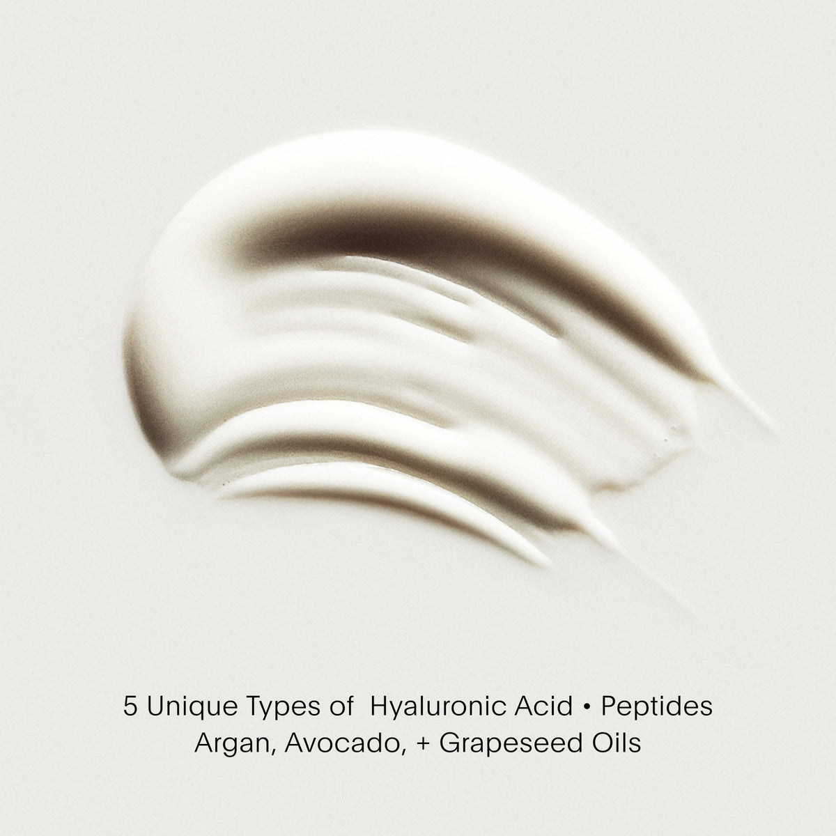 Close-up of a smooth, beige cream with text about hyaluronic acid and oils on a light gray background