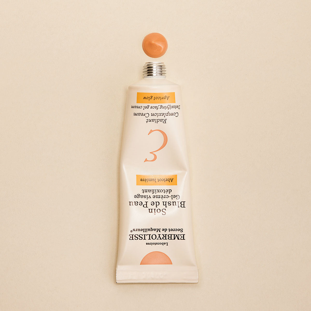 Squeezed bottle of Embryolisse Radiant Complexion Cream in Apricot Glow and a swatch of product. 