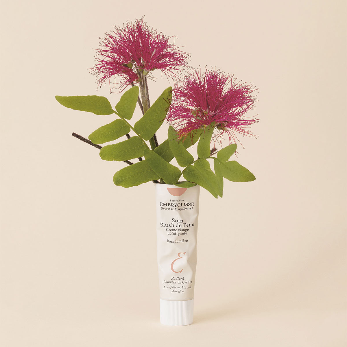 Embryolisse Radiant Complexion Cream in Rose Glow with pink flowers coming out of the top of the bottle. 