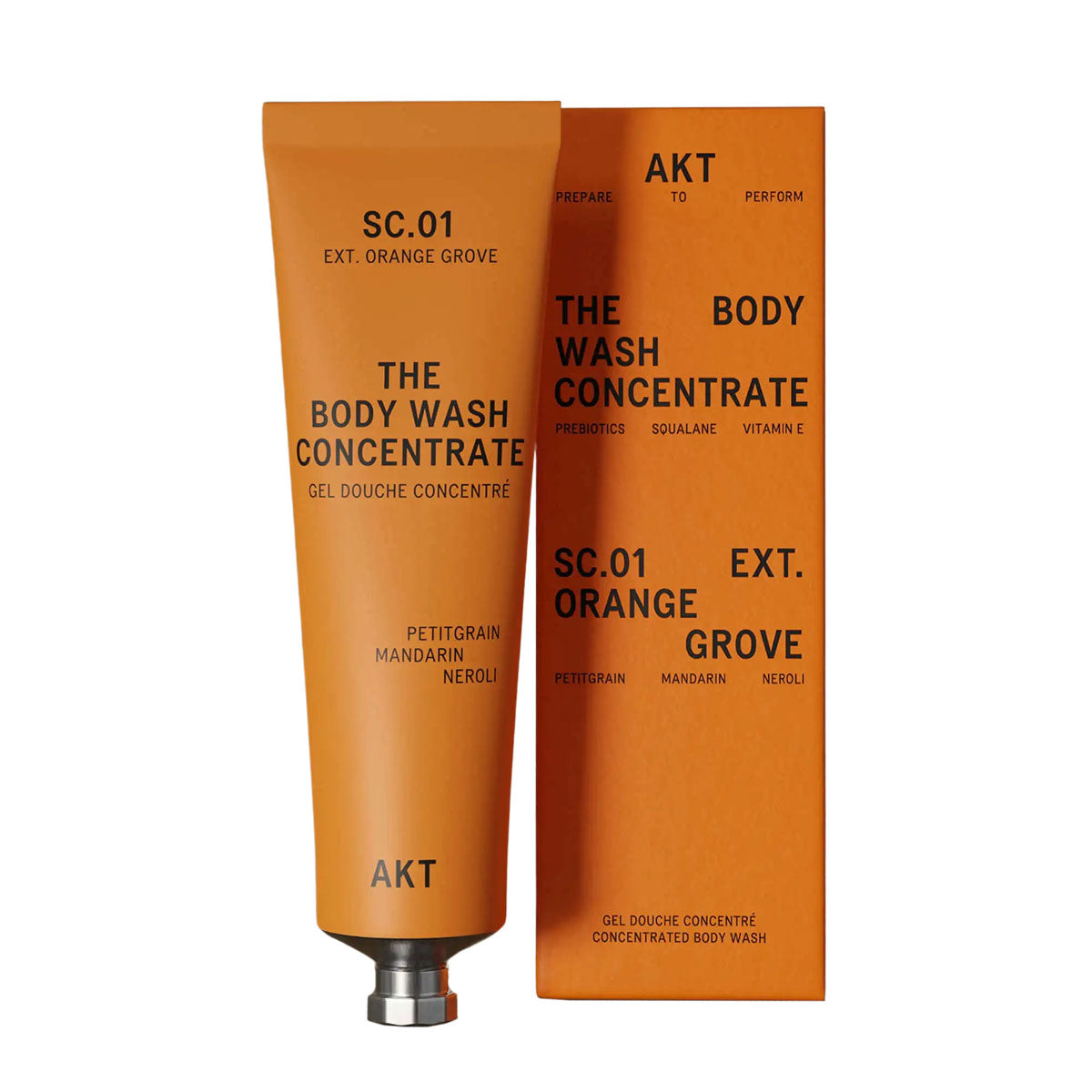 Orange tube of AKT's Body Wash Concentrate in their Orange Grove Scent next to it's orange packaging box. 