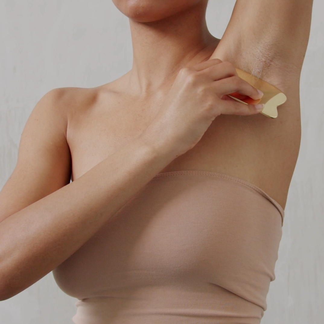 Woman using AKT's Applicator to apply their Deodorant balm to her underarms.