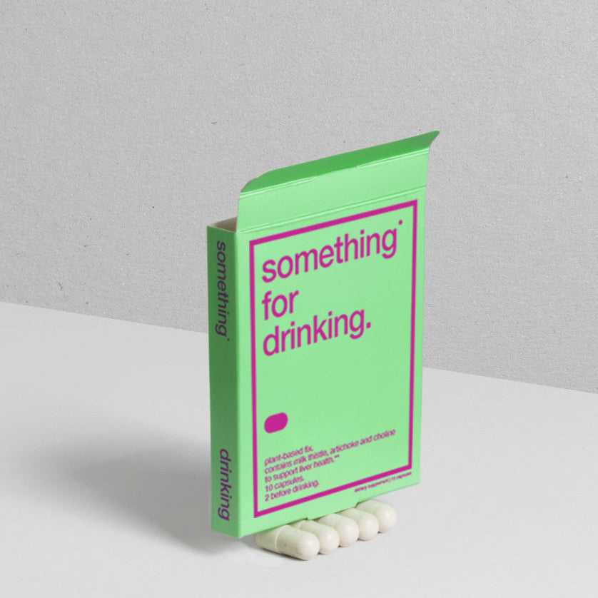 A green and pink package of 'something for drinking' containing dietary supplements for liver health on top of white pills