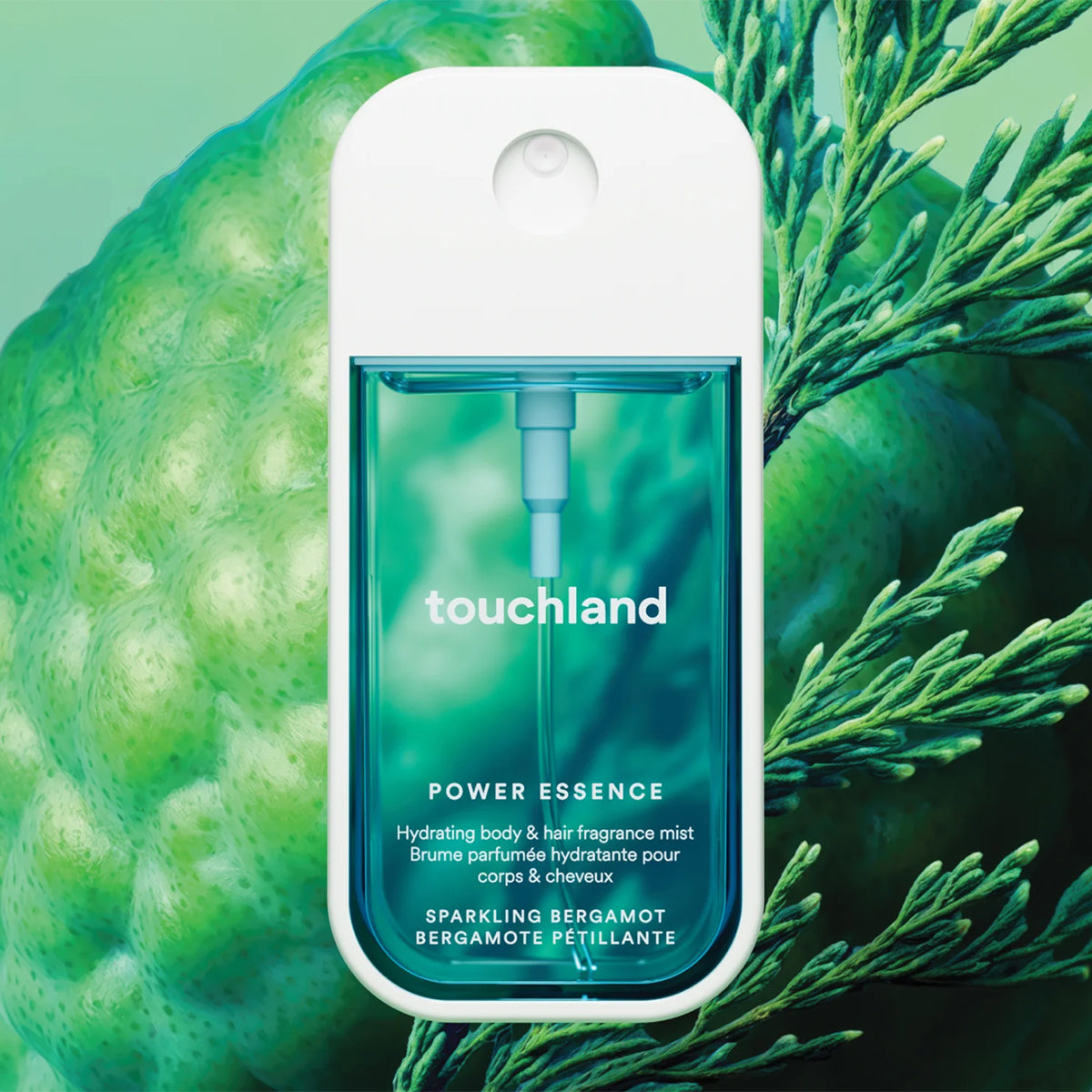 Touchland Power Essence Hydrating Body & Hair Mist with a white cap and teal-green translucent body, centered against a green botanical background with a bergamot fruit and branches.