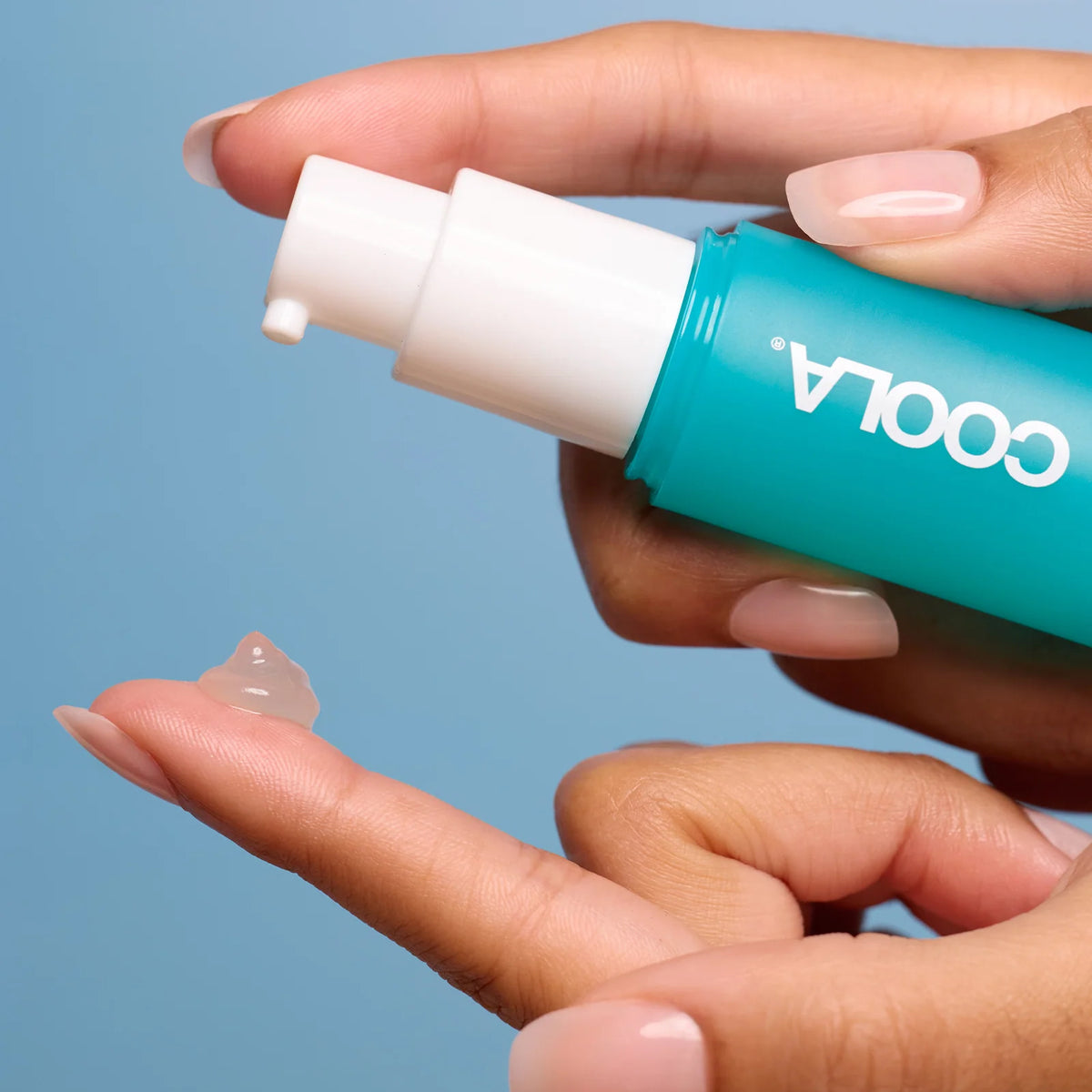 Hands expelling Coola SunBlur Primer product onto finger