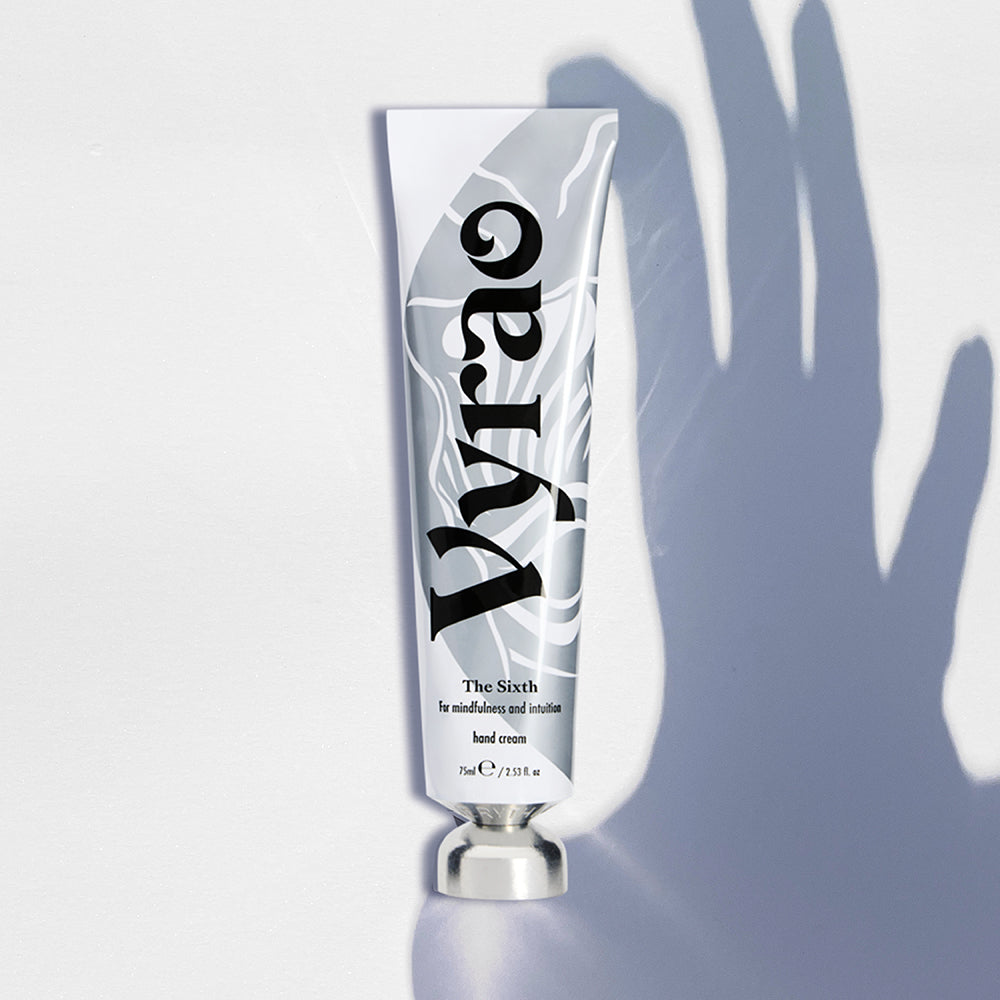 Hand cream tube labeled 'Vyrao' on a light gray background with the shadow of a hand
