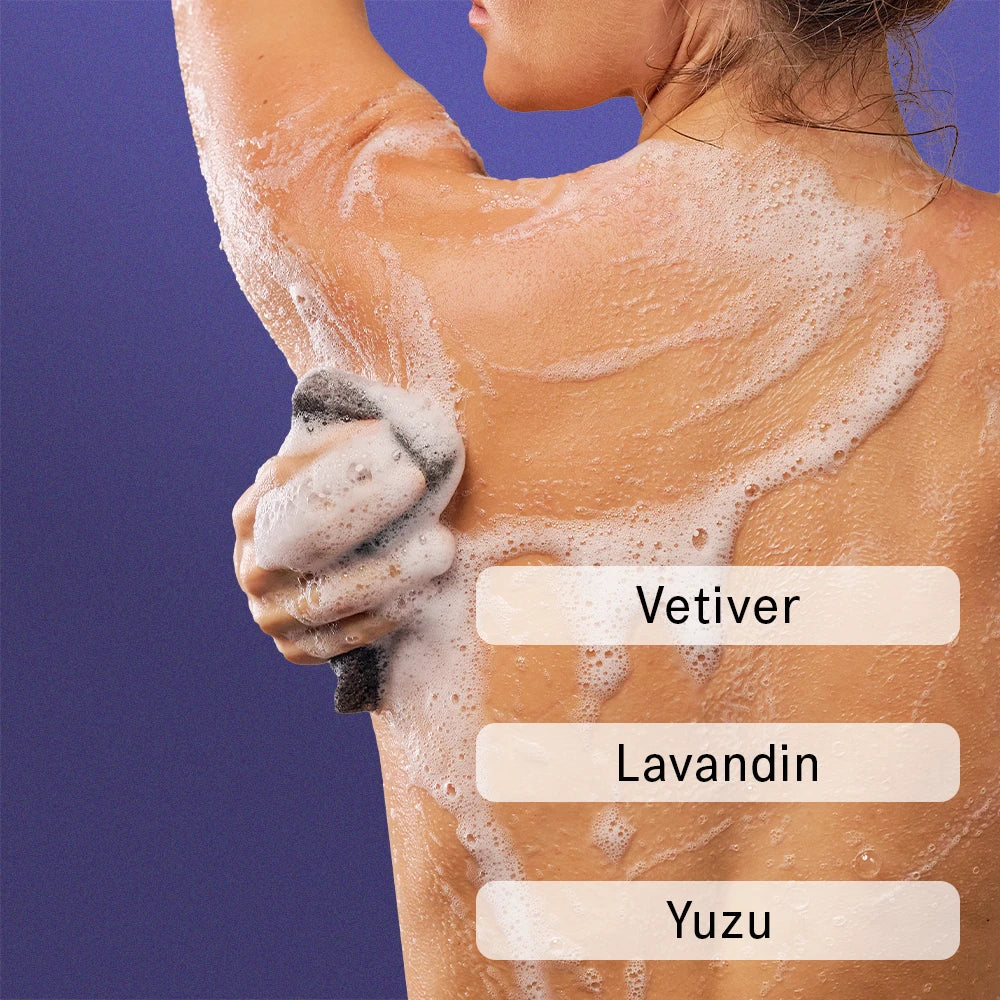 Woman using sponge to lather on sudsy body wash. Text over laid on image reads "Vetiver, Lavandin, and Yuzu."