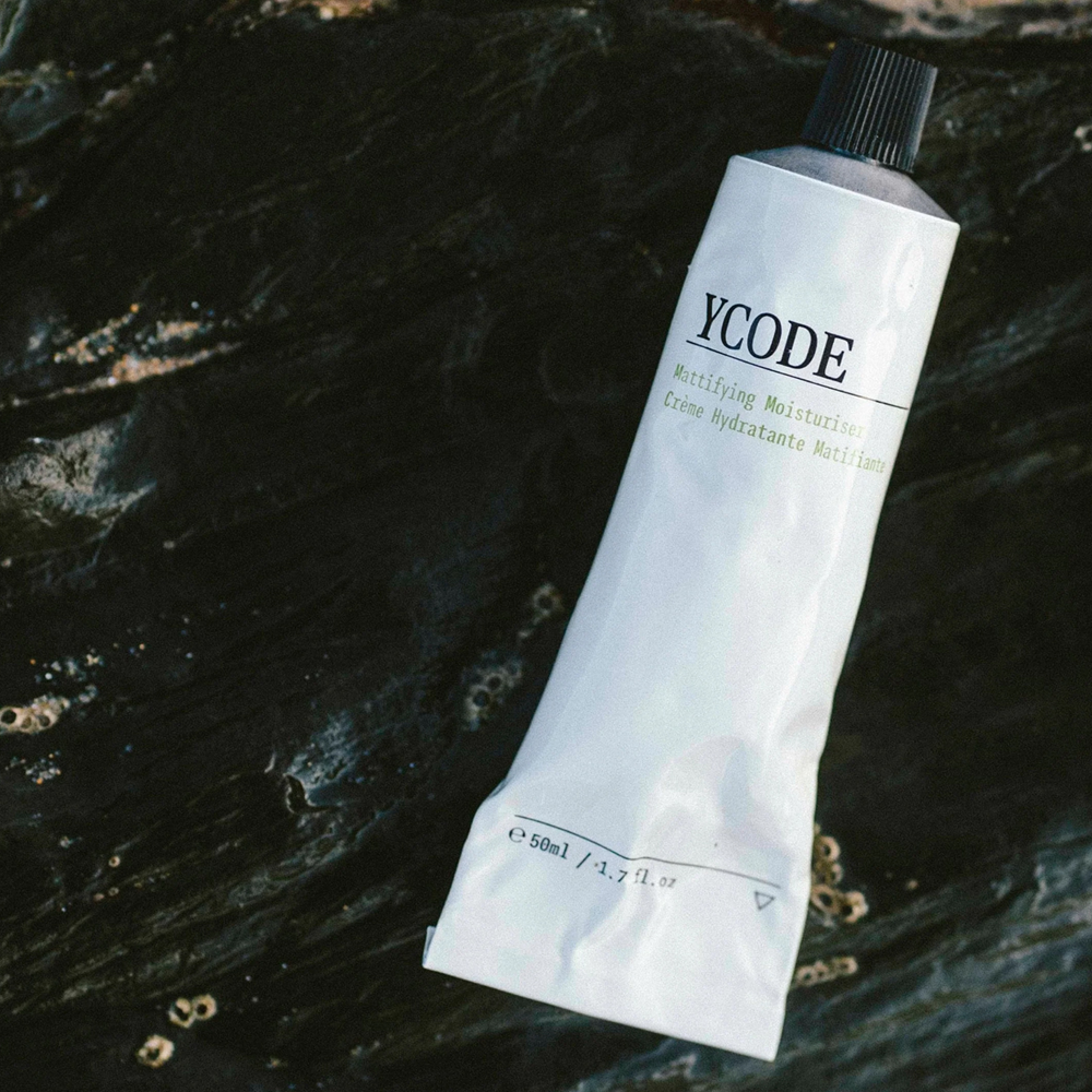 YCODE moisturizing cream tube on a dark textured surface