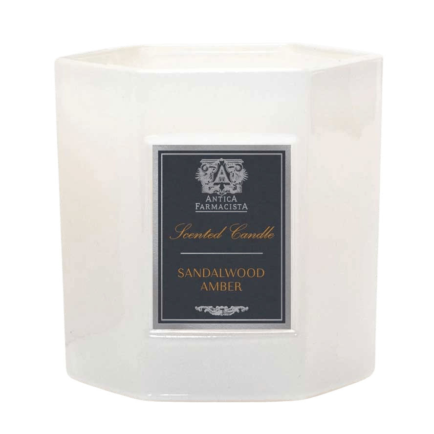 A white hexagonal candle jar with a black label that reads 'Sandalwood Amber' scented candle.