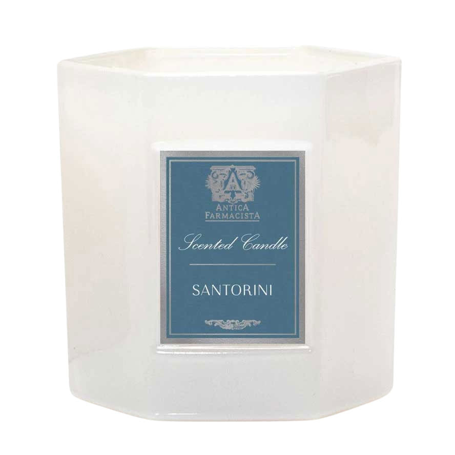 A white hexagonal candle jar with a blue label that reads 'SANTORINI' on the front, indicating the fragrance of the candle.