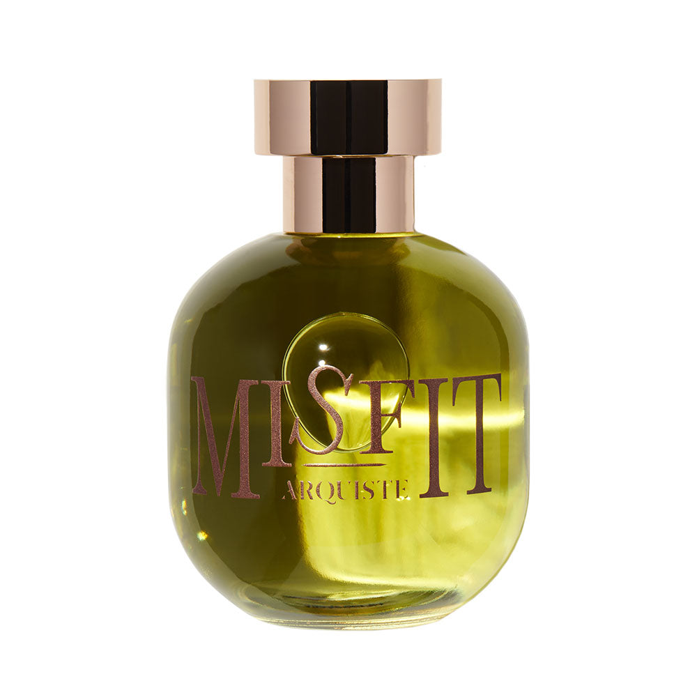 A glass bottle of Misfit Eau de Parfum with a greenish tint and a rose gold cap. The word 'MISFIT' is prominently displayed on the front in bold, white letters.