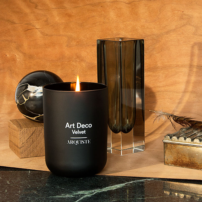 Black candle amongst various items in front of a slab of wood