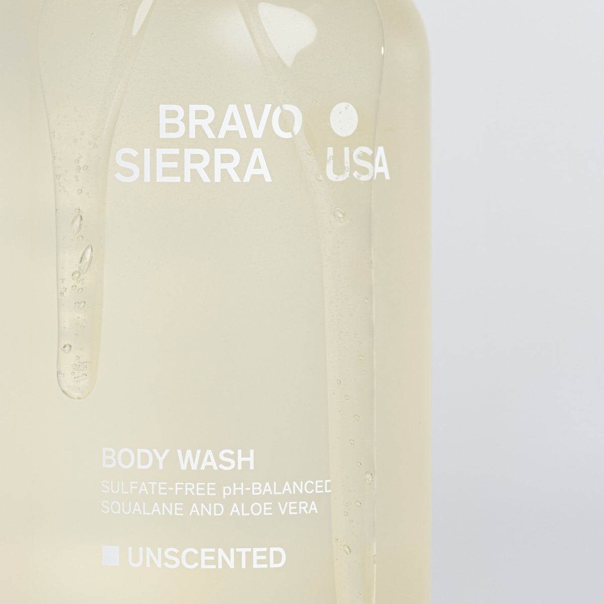 Closeup shot of the Bravo Sierra Unscented body wash bottle that has body wash dripping on it.