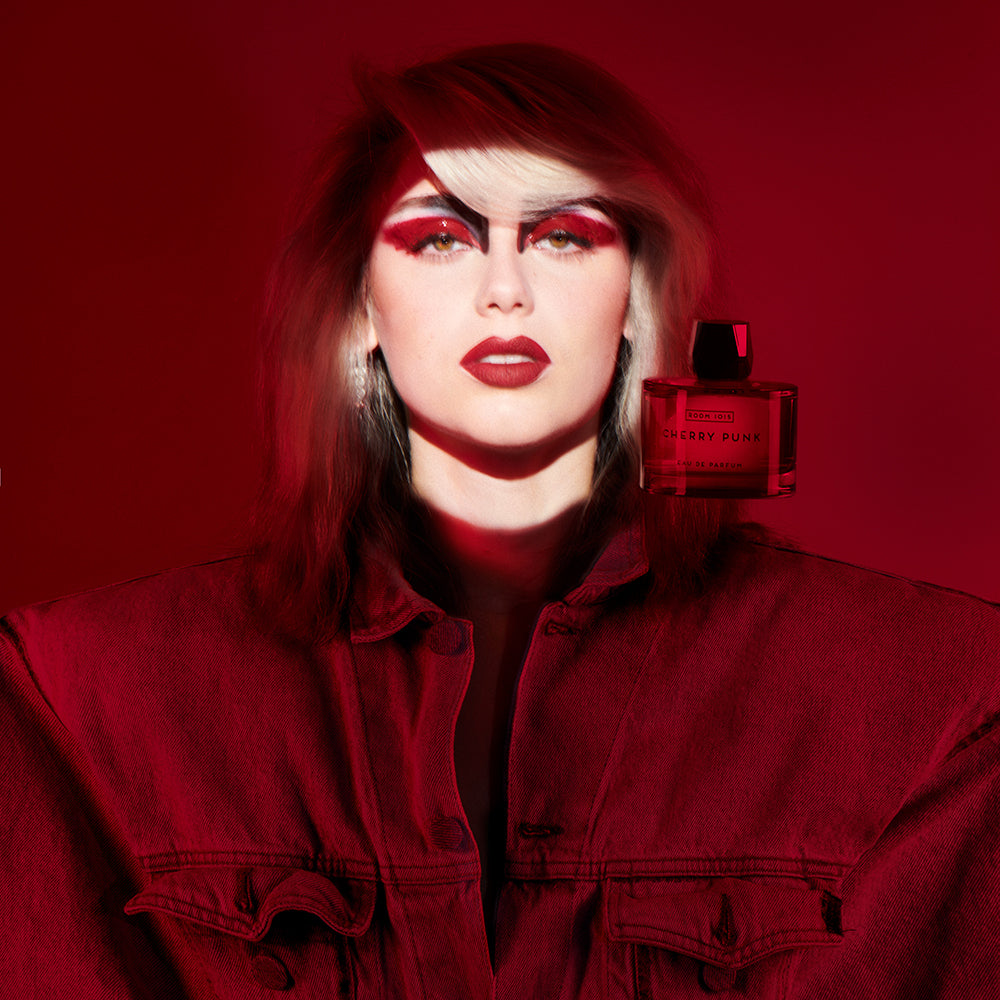 Cherry Punk - Eau de Parfum bottle floating by woman's spotlit face on a red background