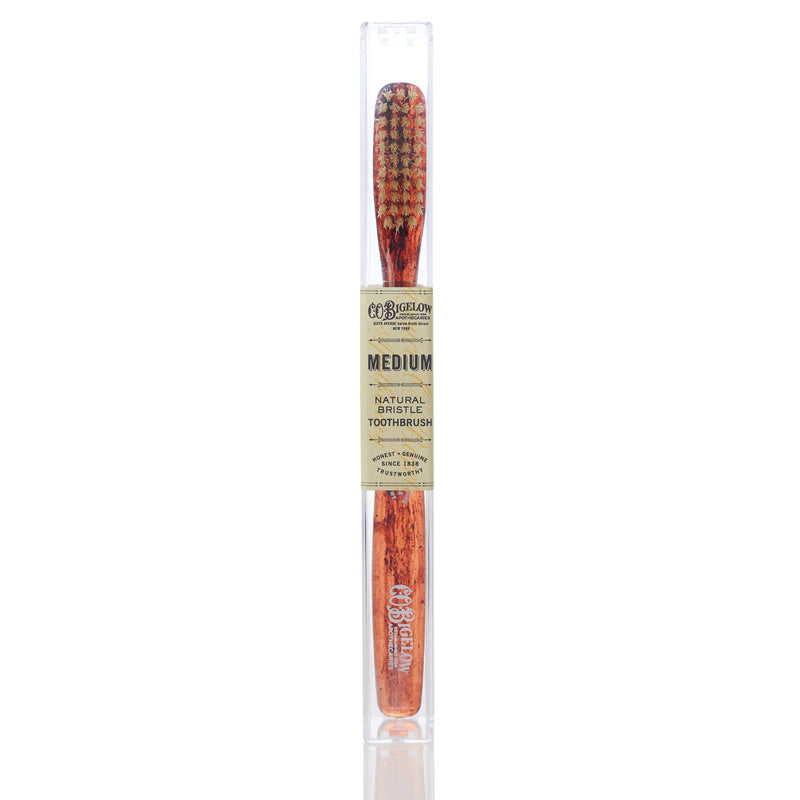 A medium bristled toothbrush with a tortoise handle, packaged in a clear plastic case with a label that reads 'C.O.