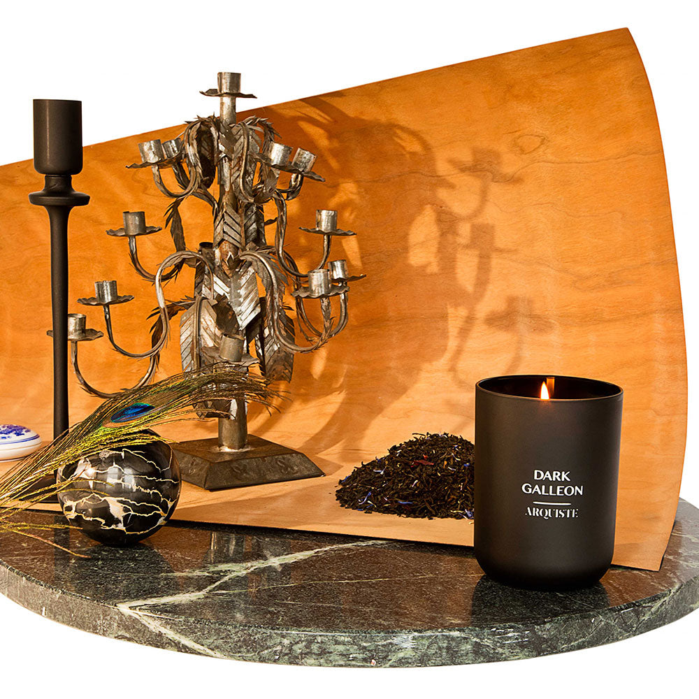 Black candle on a marble surface amongst various vintage objects