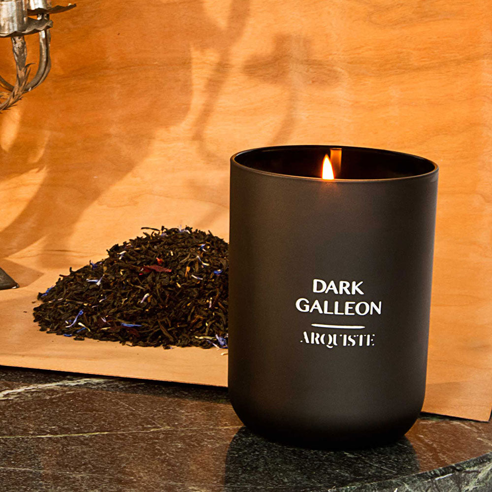 Black candle on a marble surface in front of a slab of wood