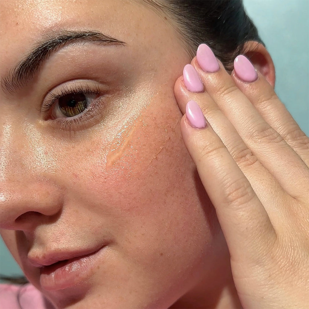Person applying a tube of Bask Daily Invisible Gel SPF 40 sunscreen to their face