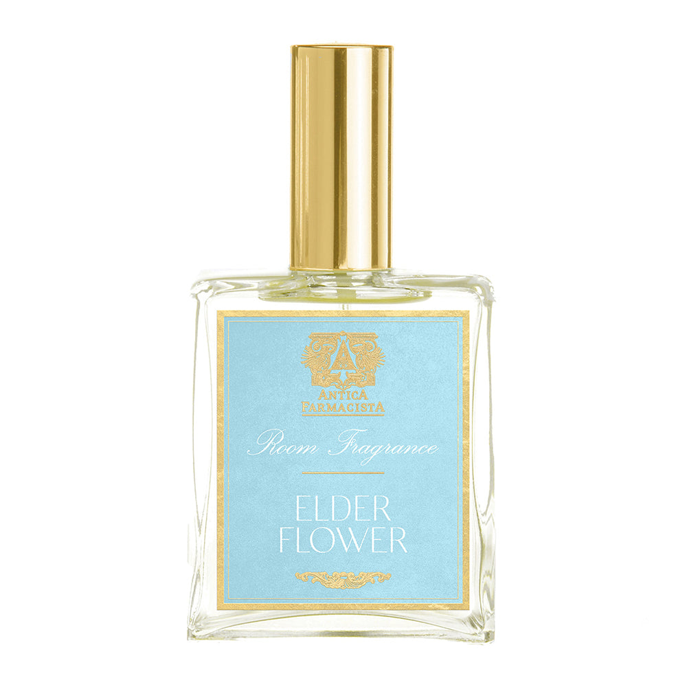 A clear glass bottle with a gold cap labeled 'Elderflower' by Antica Farmacista. The bottle is used for room spray.